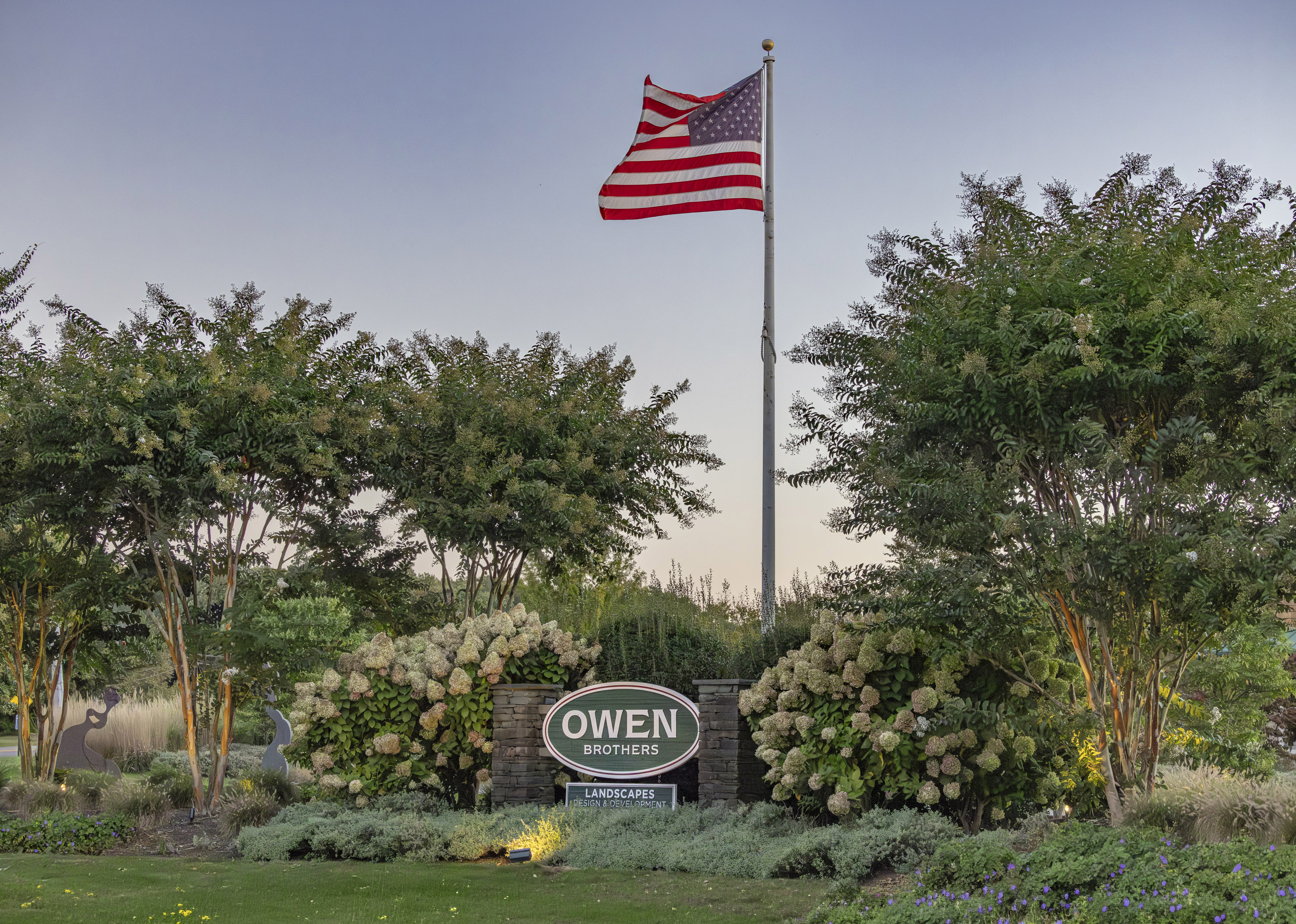 Owen Brothers Landscaping sign below US flag